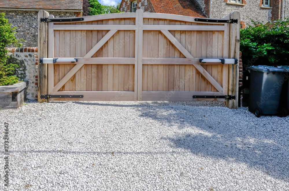 Wooden driveway gate at countryside house with gravel